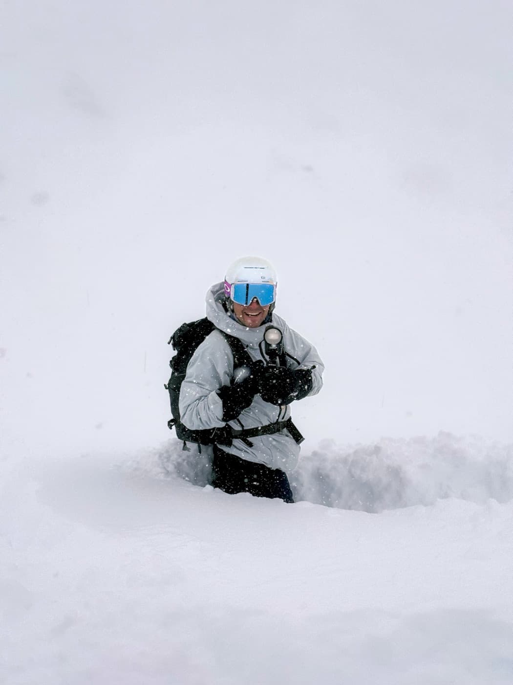 Photographe au travail hors-piste dans les Trois Vallées, appareil et flash en poudreuse